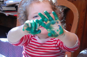 Kind mit grüner Fingerfarbe